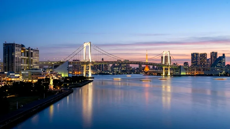 Rainbow Bridge and Tokyo skyline over calm Tokyo Bay at blue hour.